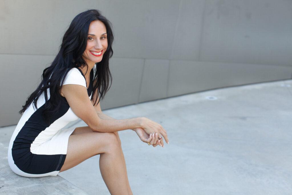 DrSaidaDesilets in white dress wtih black stripe sitting on step